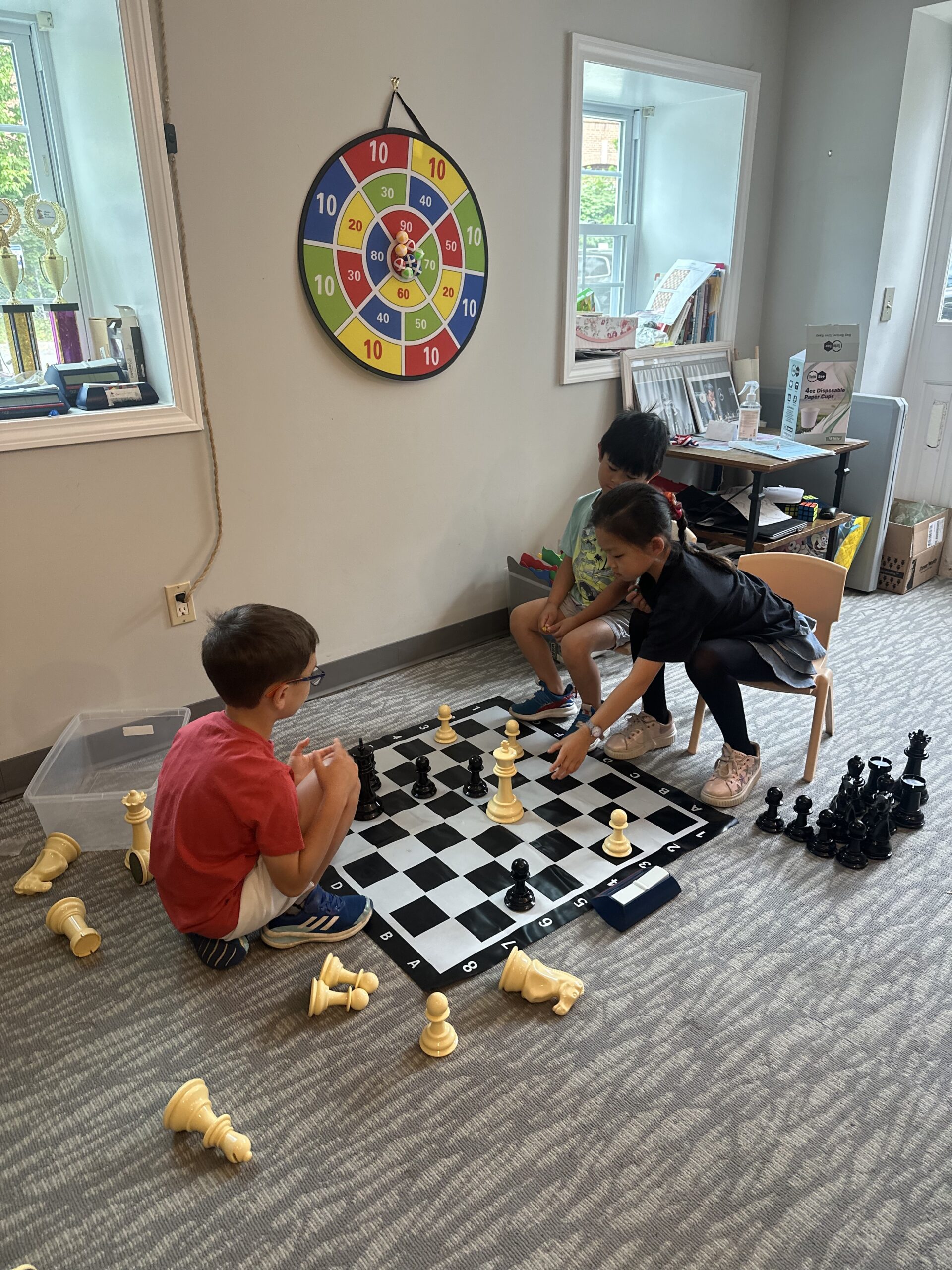 Campers playing chess on a large floor board