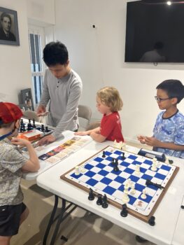 Children practicing chess on a large demonstration board at Chess Max Academy
