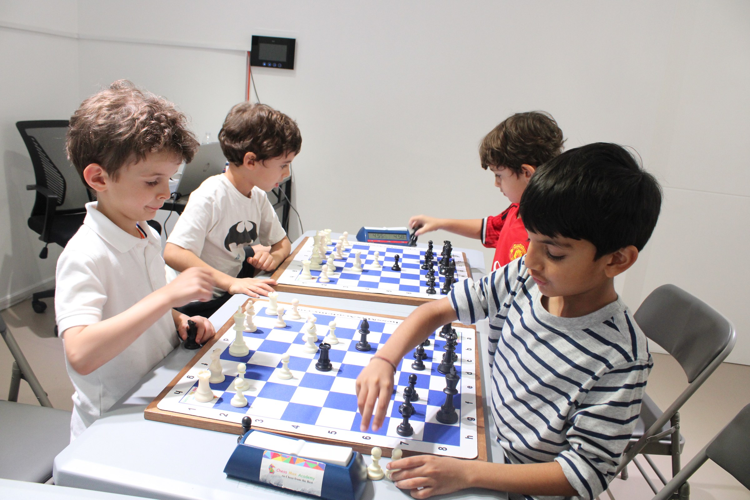 Children practicing chess with a coach during an Upper West Side group class